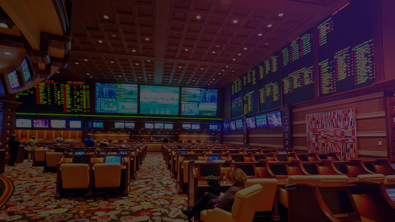 Photo: the sportsbook at Wynn Las Vegas, rows of seats facing walls of odds boards and screens.